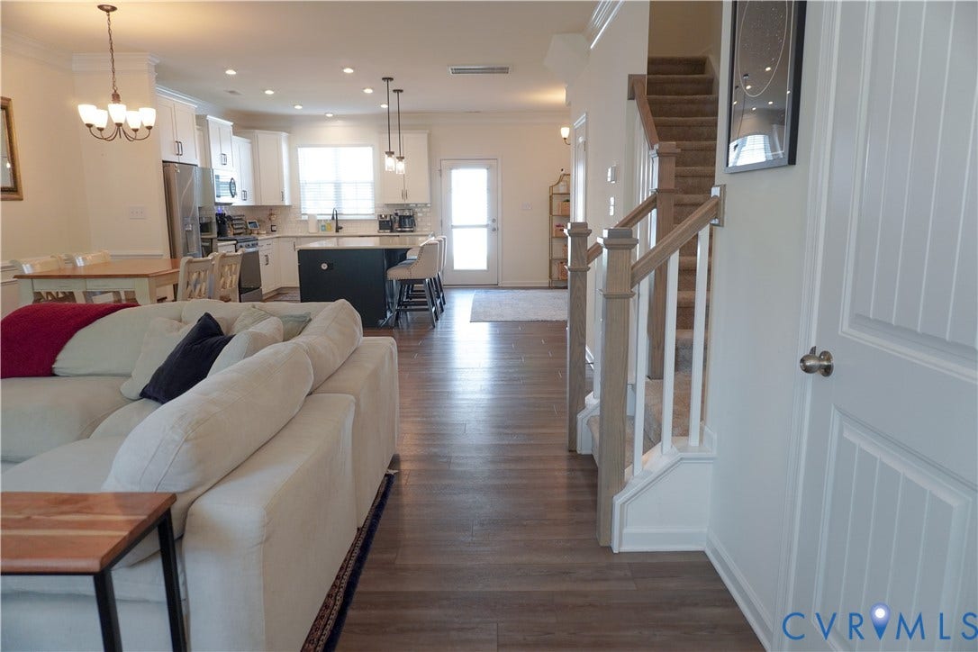 Open-concept living area with wood-finish flooring, white cabinetry, a kitchen island, and stainless steel appliances