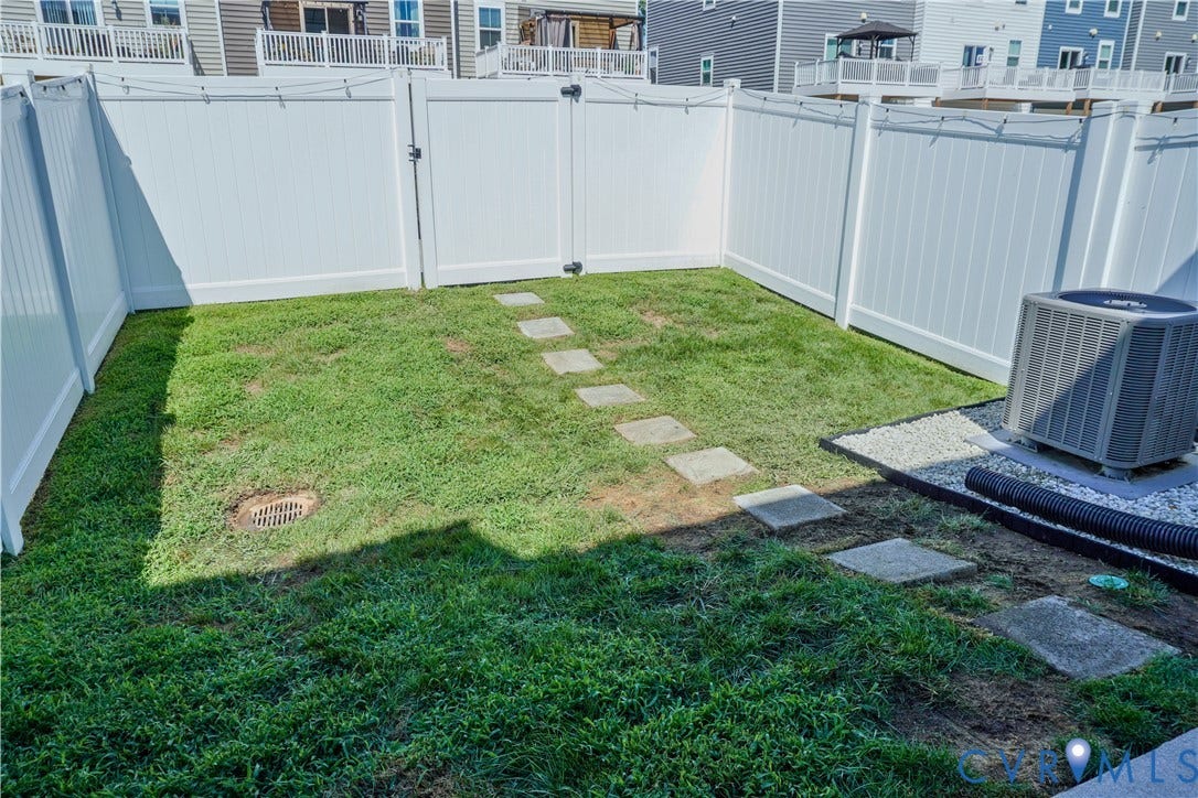 Private enclosed yard featuring a white privacy fence, stepping stones, and a gravel pad