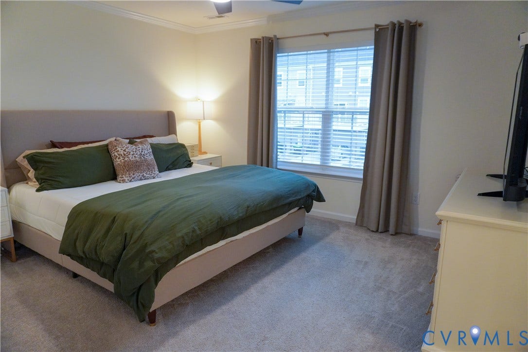 Wall-to-wall carpeting, crown molding, a ceiling fan, and a window with blinds