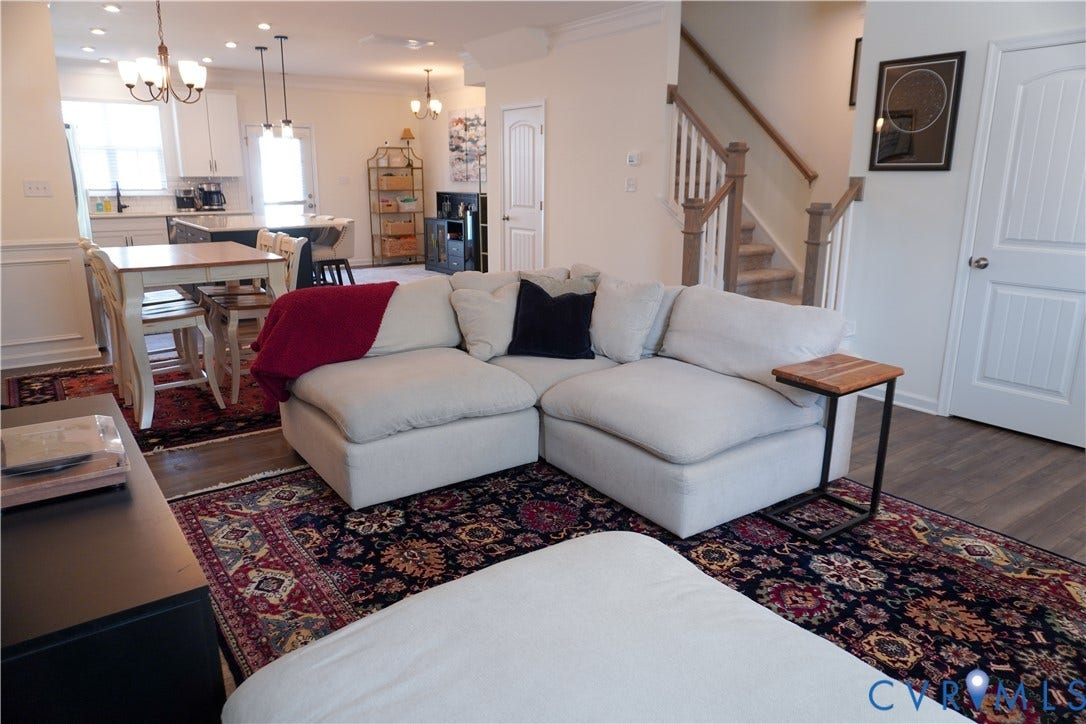Wood-finish flooring throughout, white painted baseboards, and a white paneled door