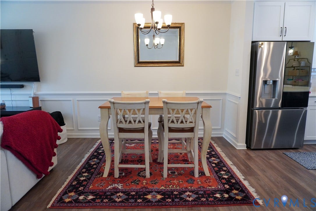Wood-finish flooring, wainscoting, and a chandelier with glass shades