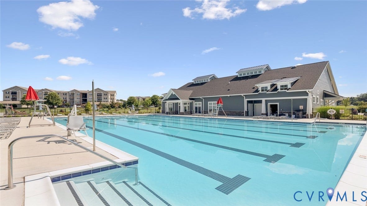 Community swimming pool with lane markers, integrated steps, and a surrounding concrete deck