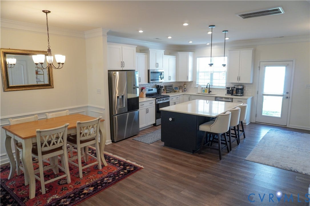 Contemporary kitchen with white cabinetry, stainless steel appliances, and a central island with countertop seating