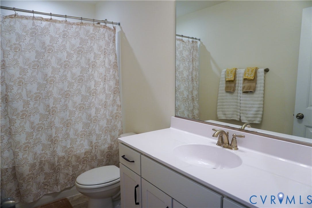 White vanity with an integrated sink, brushed nickel faucet, and a large wall-mounted mirror