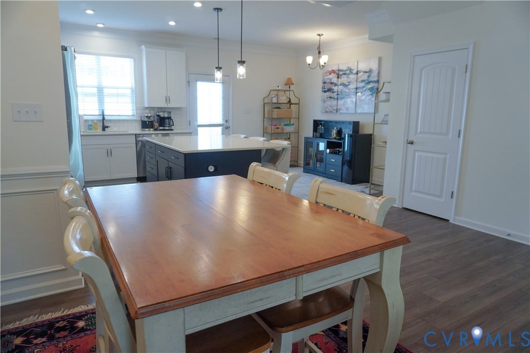 Open-concept living space with wood-finish flooring, recessed lighting, and a white paneled door