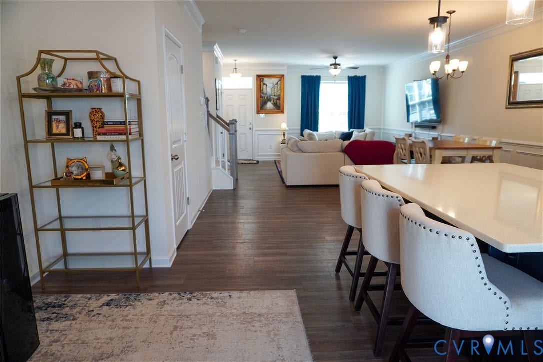 Open-concept living space featuring wood-finish flooring, a kitchen island with seating, a dining area, and a living room