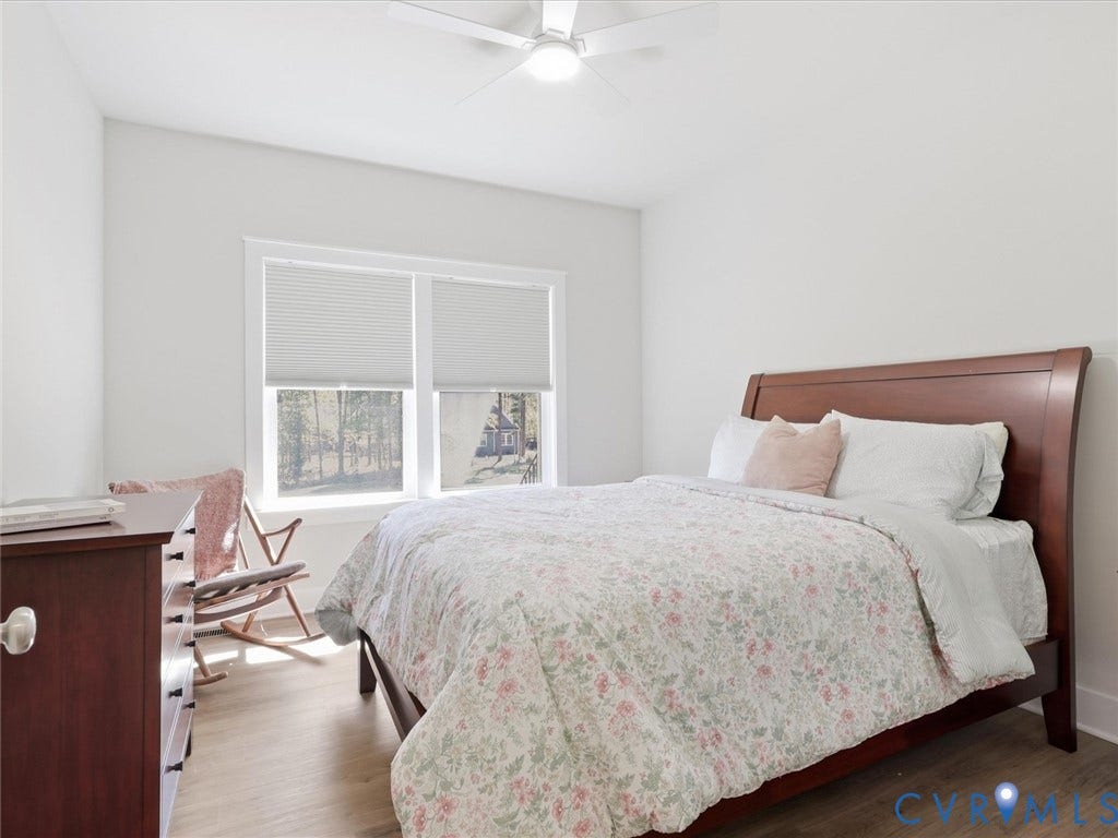3102 Kensington Lane, Goochland, VA 23063 Light-toned wood-finish flooring, two large windows with privacy blinds, and a ceiling fan with integrated lighting