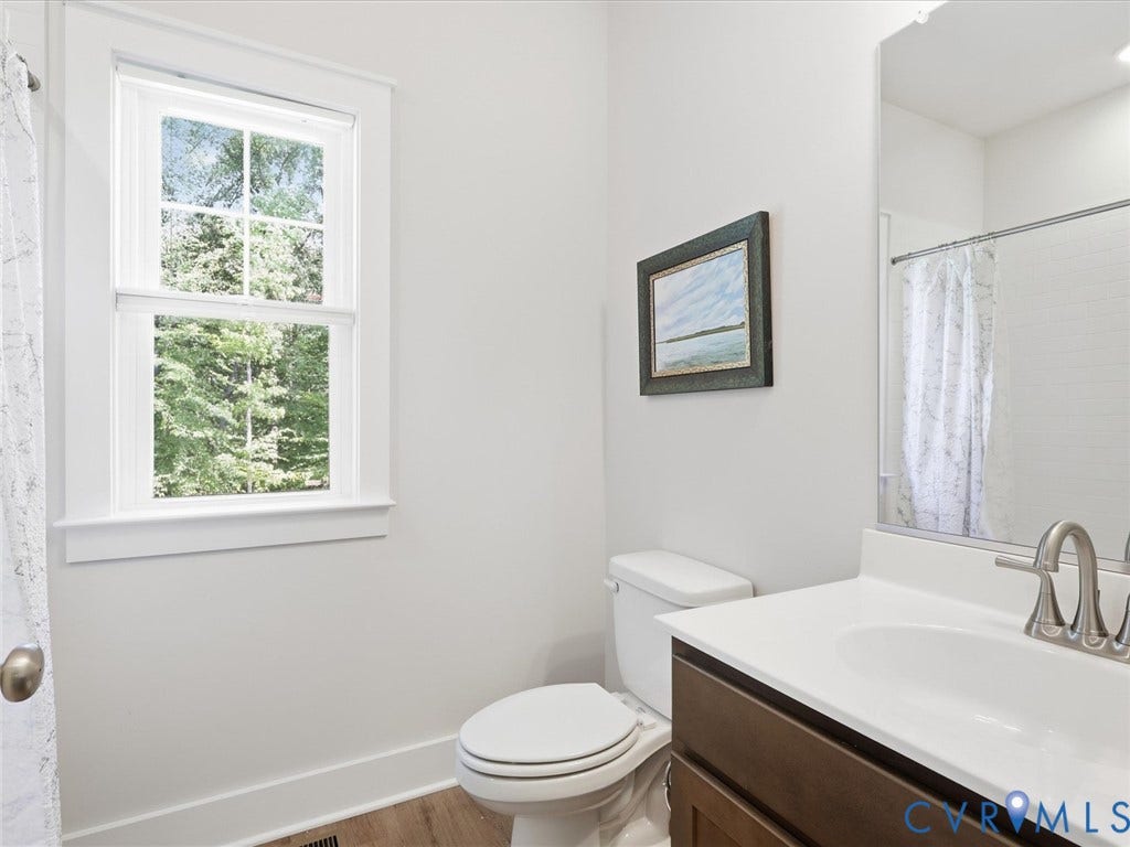3102 Kensington Lane, Goochland, VA 23063 White double-hung window, wood-finish flooring, white vanity countertop, brushed nickel faucet, and a built-in mirror