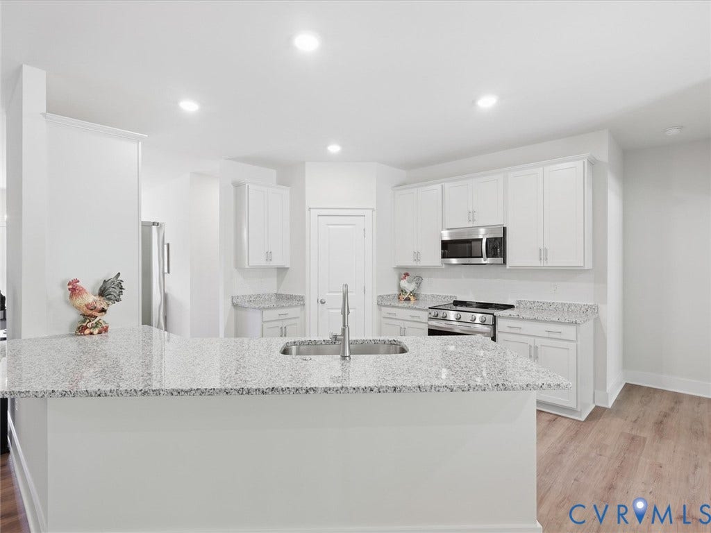 3102 Kensington Lane, Goochland, VA 23063 Kitchen featuring white shaker-style cabinetry, stainless steel appliances, speckled stone countertops, and wood-finish flooring