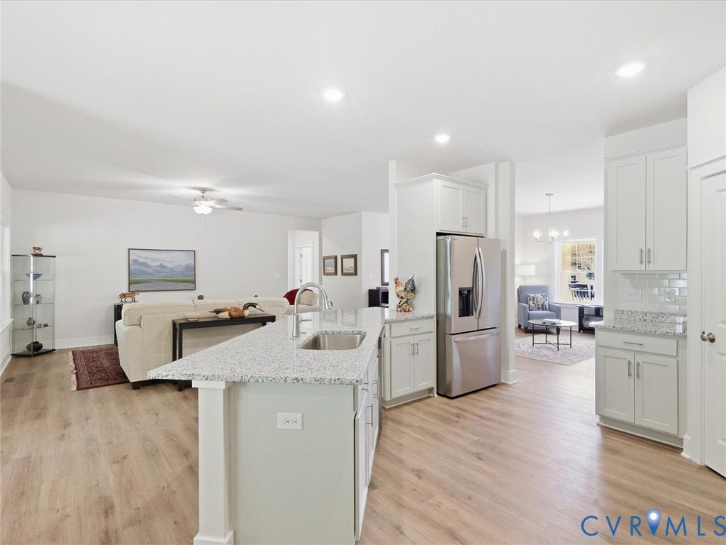 3102 Kensington Lane, Goochland, VA 23063 Wood-finish flooring throughout, white cabinetry, recessed lighting, stainless steel appliances, and a kitchen island with a built-in sink