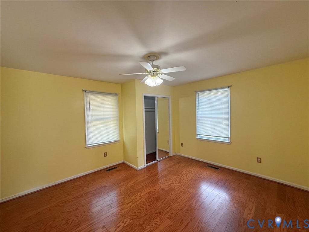 4512 Greenbriar Drive, Chester, VA 23831 Wood-finish flooring, bright yellow walls, dual windows with blinds, mirrored closet doors, and a ceiling fan with integrated lighting