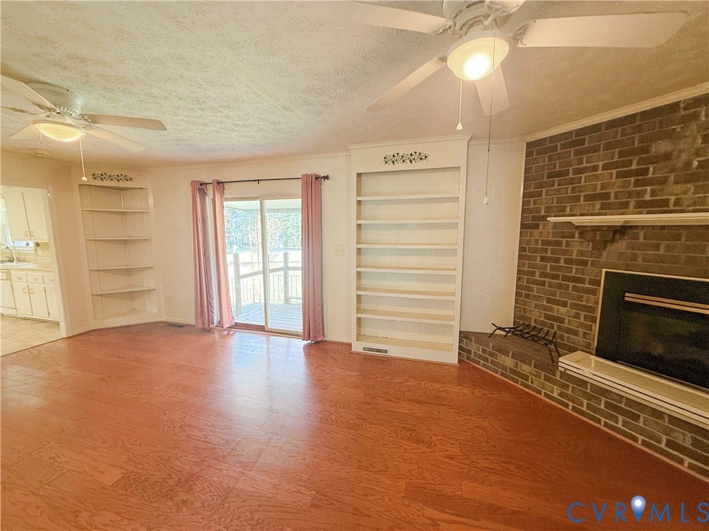 4512 Greenbriar Drive, Chester, VA 23831 Wood-finish flooring, brick fireplace with mantel, built-in shelving, glass sliding door, and two ceiling fans with integrated lighting
