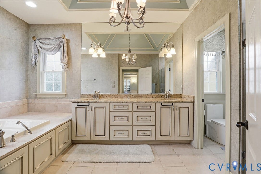 Dual vanity with integrated sinks, built-in cabinetry, and a large wall-mounted mirror