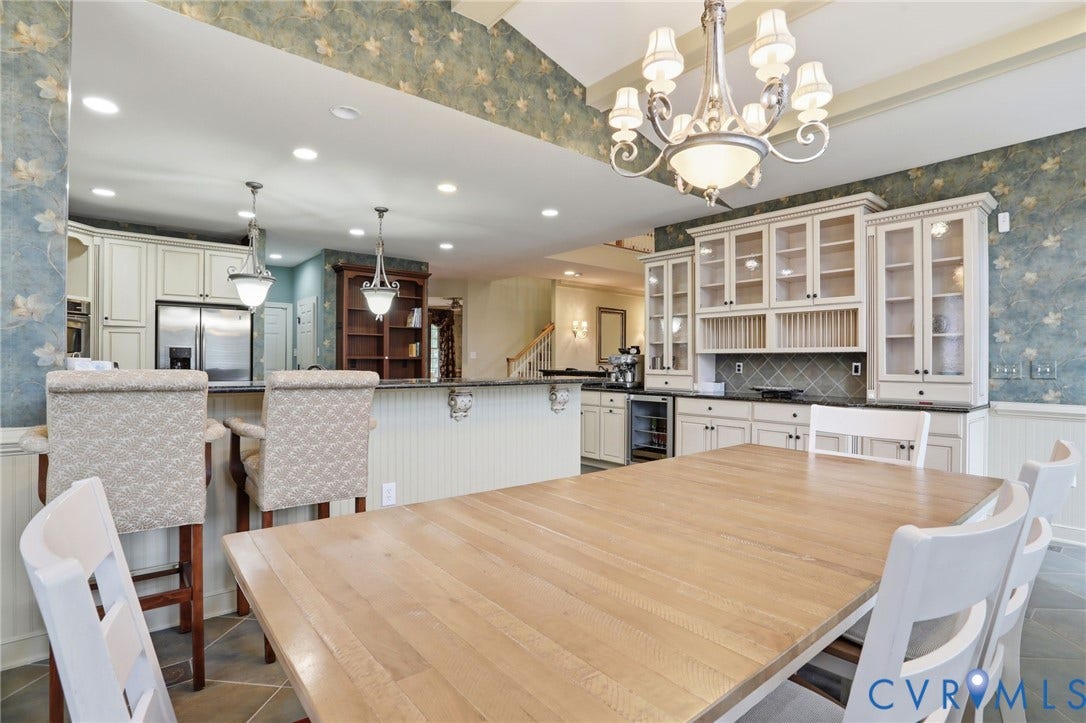 Kitchen with cream-colored cabinetry, black countertops, and a built-in wine cooler