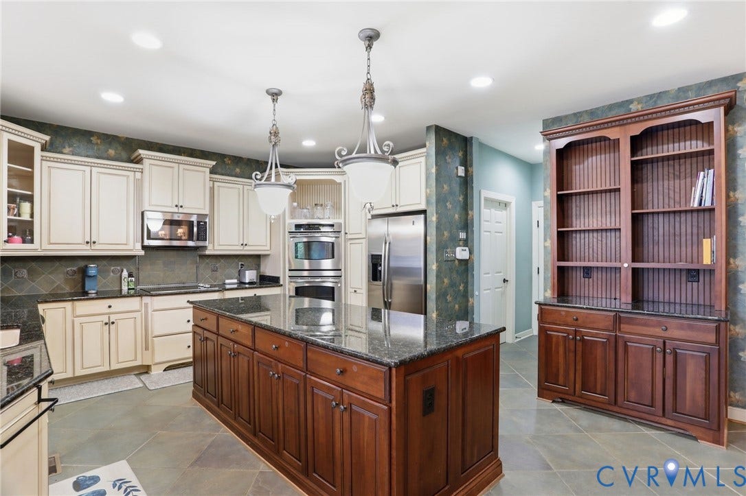 Spacious kitchen featuring an expansive central island, double wall ovens, built-in stainless steel refrigerator, and recessed lighting