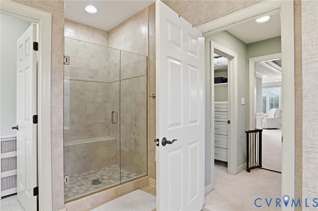 Walk-in shower with clear glass enclosure, tiled walls, built-in bench, and recessed lighting