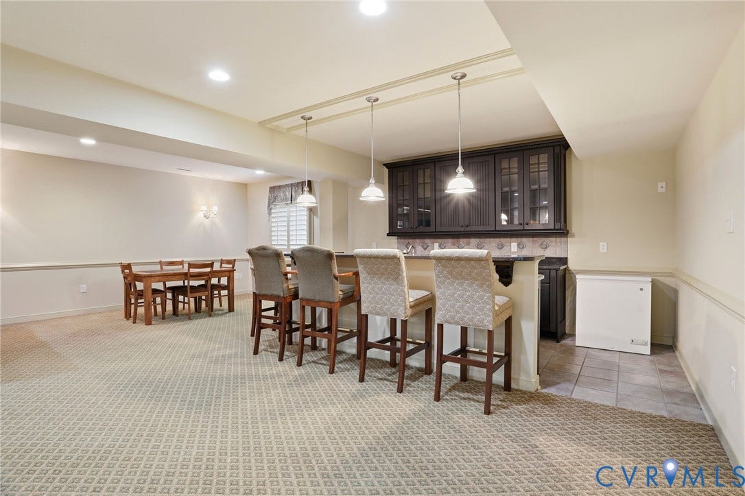 Recessed lighting, built-in wet bar with dark cabinetry, stone backsplash, and pendant lighting
