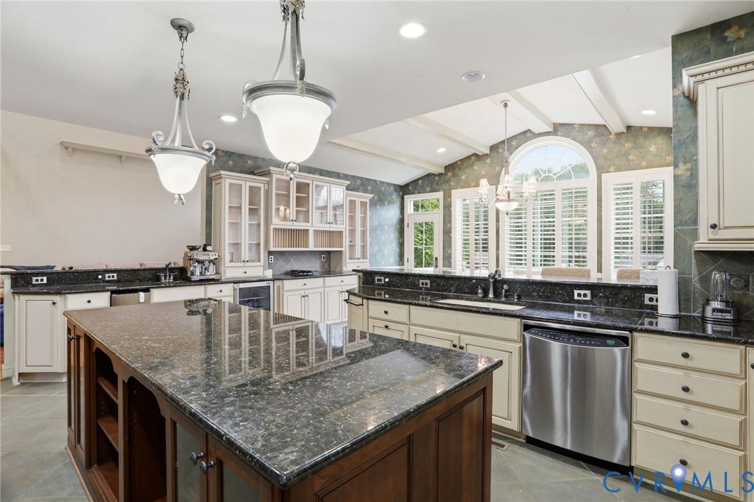 Kitchen featuring a large central island, dark granite countertops, cream-toned cabinetry, and stainless steel appliances