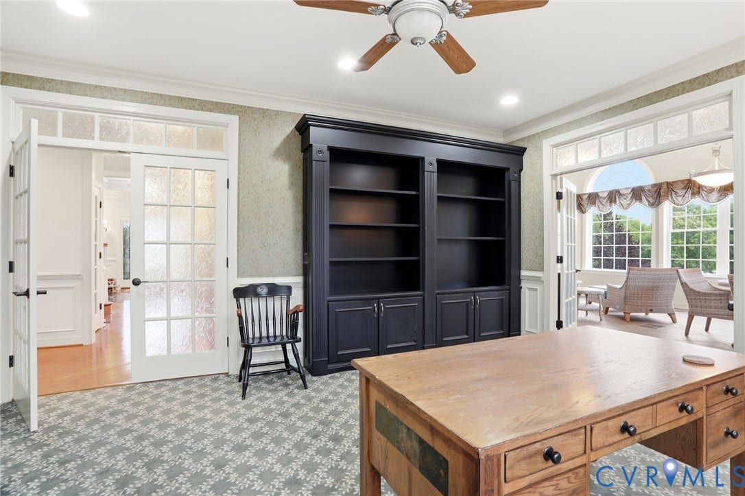 Built-in bookcase, patterned carpeting, French doors with transom windows, ceiling fan, and recessed lighting
