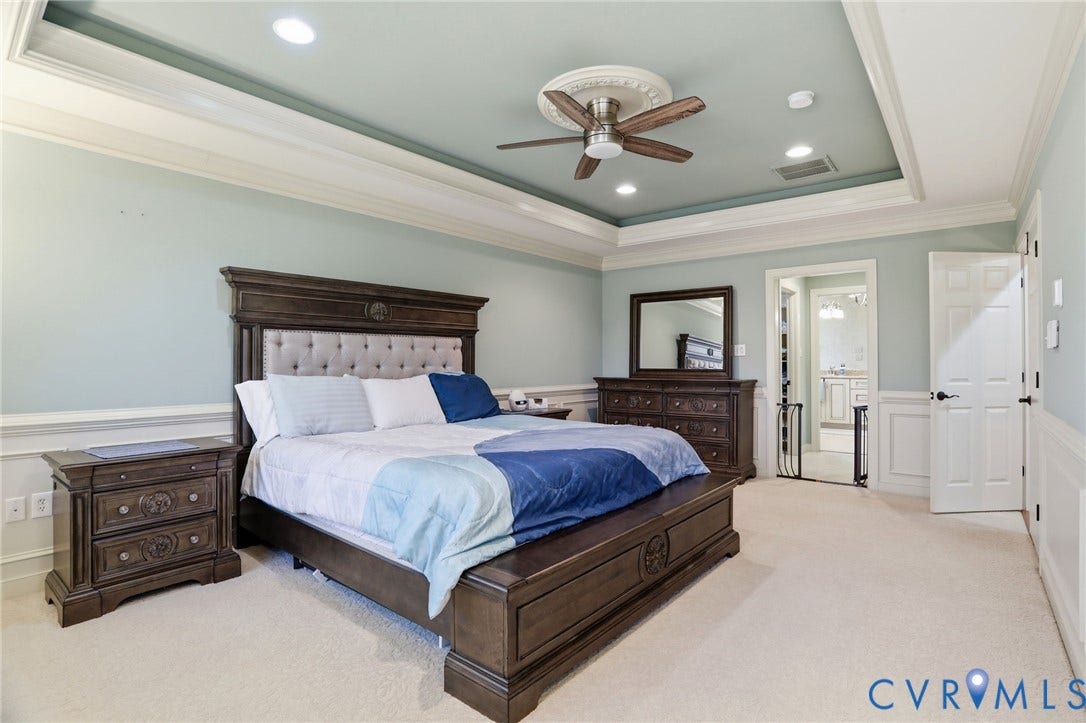 Recessed lighting, tray ceiling, ceiling fan, crown molding, and wainscoting