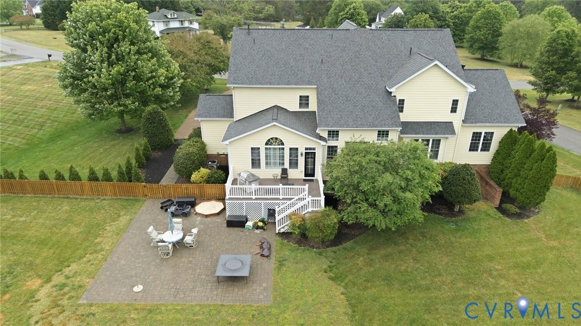Expansive backyard featuring a paver patio, wood privacy fence, and manicured lawn