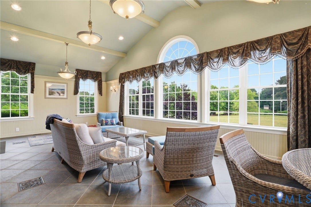 Vaulted ceiling with exposed beams, recessed lighting, expansive windows with an arched transom, tile flooring, and wainscoting details
