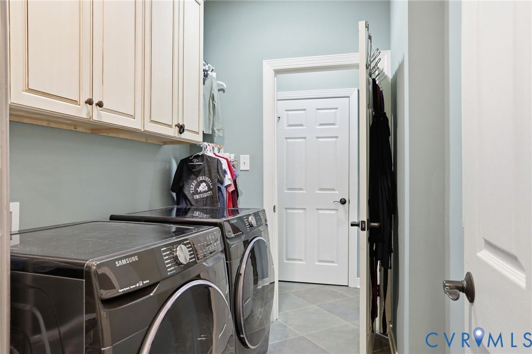 White shaker-style cabinetry with dark hardware, a tiled floor, and a built-in hanging rack