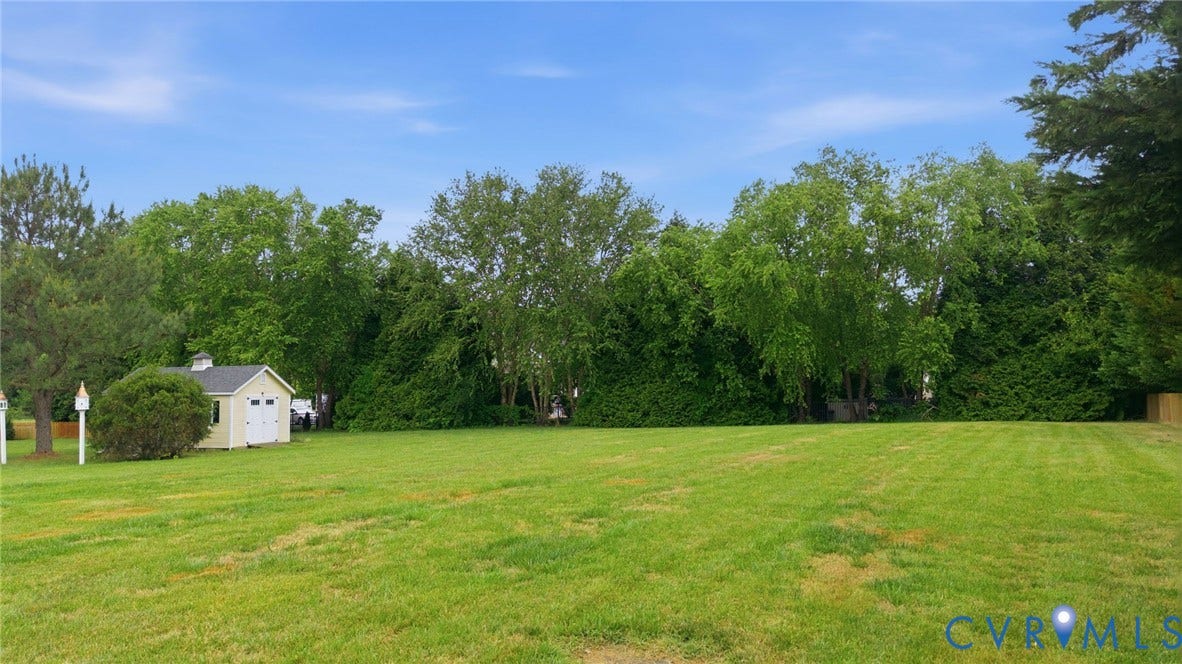Expansive green lawn with a detached storage shed featuring a white door and cupola