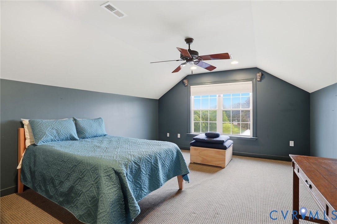 Vaulted ceiling with a ceiling fan, dual windows, and carpet flooring