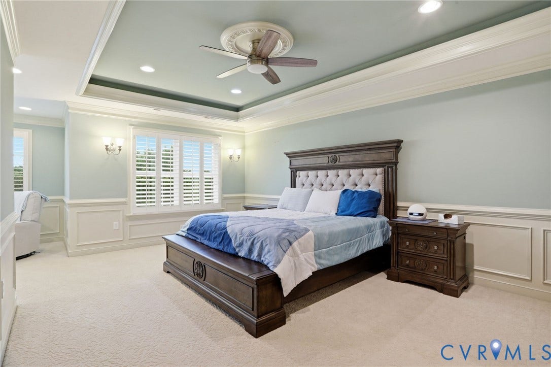 Recessed lighting, crown molding, a tray ceiling with a ceiling fan, and sconce lighting