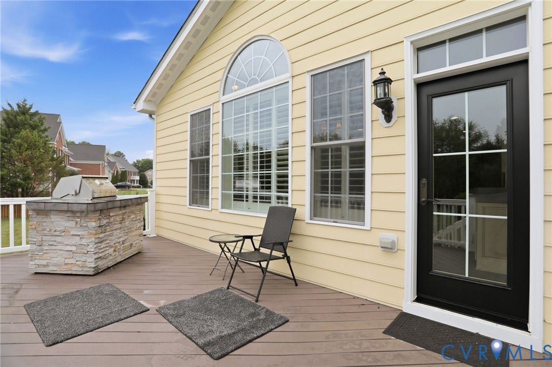 Composite deck with a built-in outdoor grill, stone veneer base, and white railing