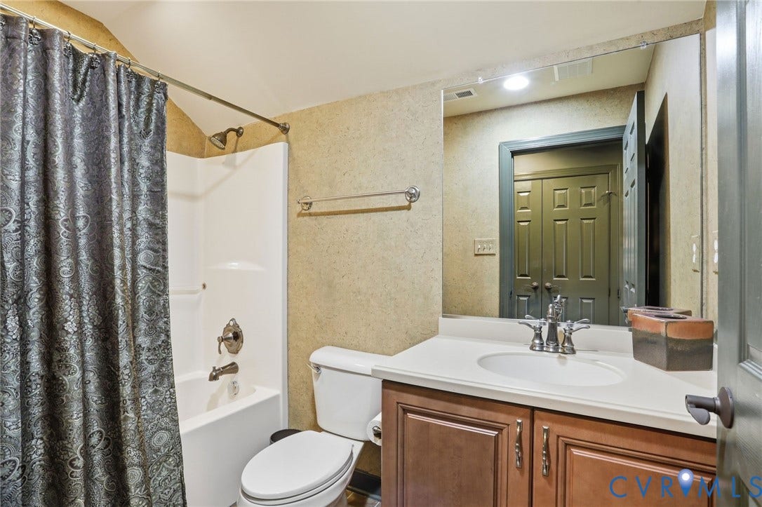 Full bathroom featuring a shower-tub combination with chrome fixtures, a single vanity with a white countertop, and wood-finish cabinetry