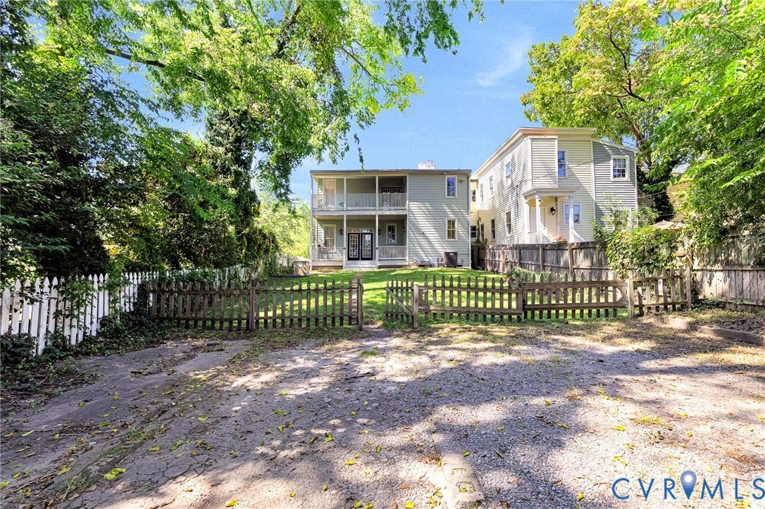 615 N 23rd Street, Church Hill Central, Richmond, VA 23223 Multi-level exterior with multiple balconies, a gravel parking area, and a picket fence