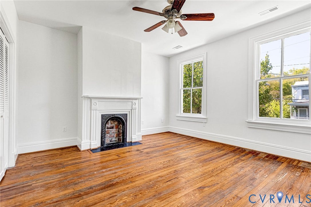 615 N 23rd Street, Church Hill Central, Richmond, VA 23223 Hardwood flooring, two large windows, white decorative fireplace with black insert, ceiling fan, and bi-fold closet