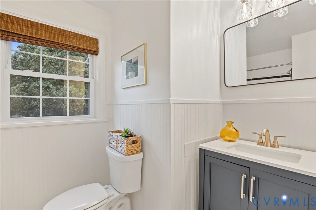 3353 Warner Road, Stratford Hills, Richmond, VA 23225 White paneled walls, a white window frame, a dark gray vanity with a white countertop, and a rectangular mirror