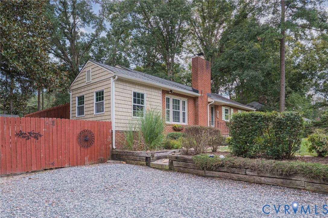 3353 Warner Road, Stratford Hills, Richmond, VA 23225 Brick and shake siding exterior with a prominent brick chimney, gravel driveway, and a red wooden fence