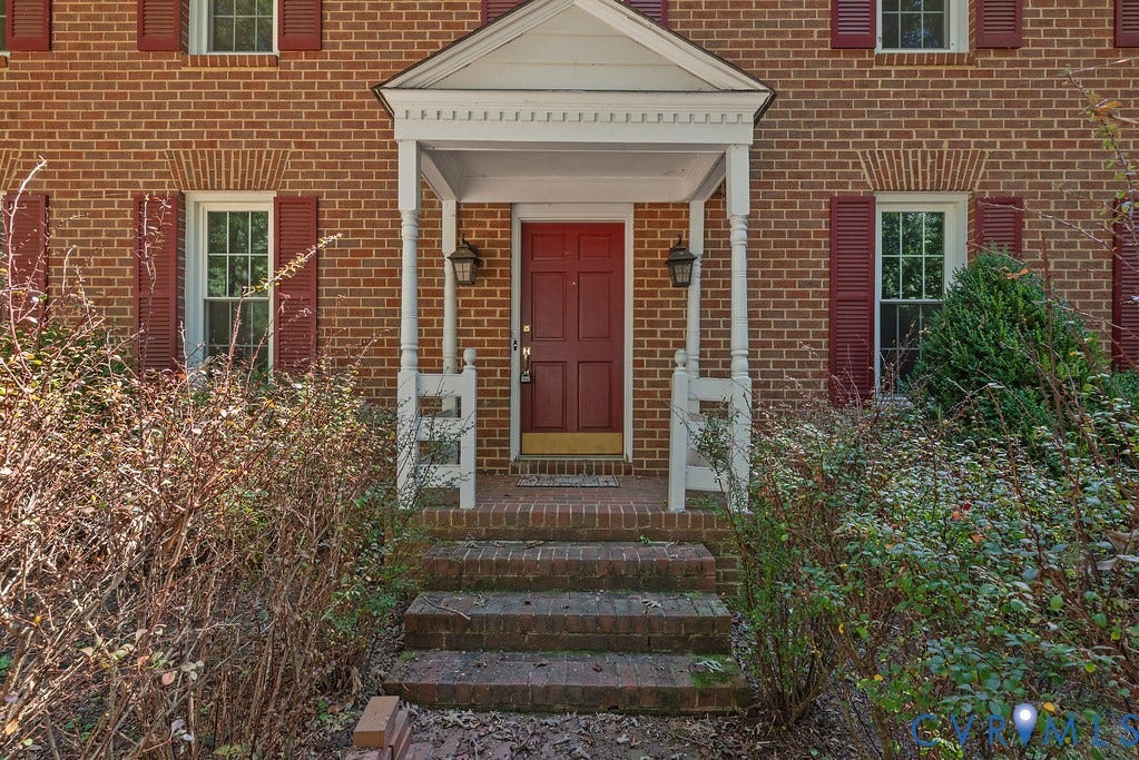 13830 Hailsham Circle, Salisbury, Midlothian, VA 23113 Brick facade with red shutters, featuring a covered porch entry with white columns and railings, and a red paneled front door