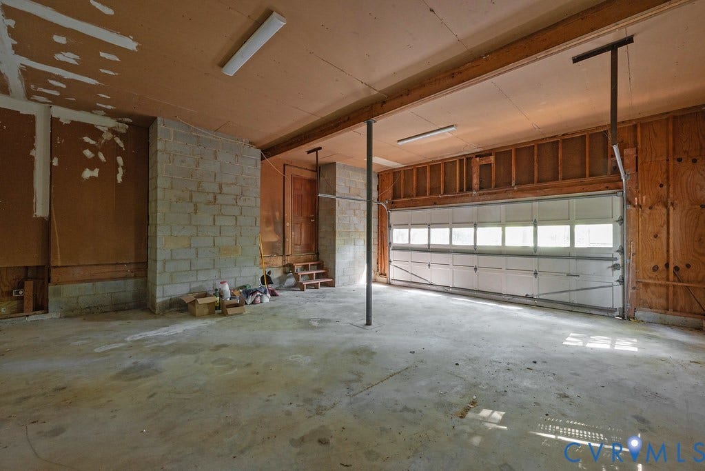 13830 Hailsham Circle, Salisbury, Midlothian, VA 23113 Concrete flooring, exposed block wall, exposed wood framing, overhead fluorescent lighting, and a paneled garage door
