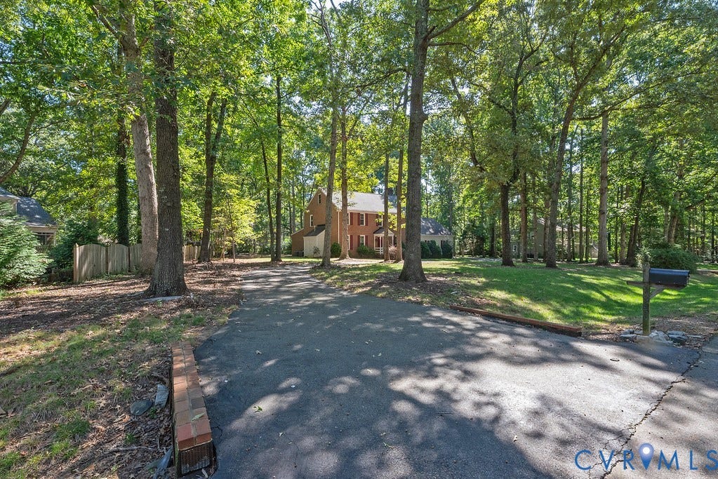 13830 Hailsham Circle, Salisbury, Midlothian, VA 23113 Paved driveway leading to a brick residence with white trim and shuttered windows, surrounded by mature trees and a manicured lawn