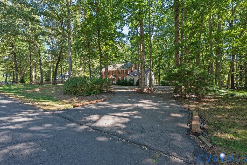13830 Hailsham Circle, Salisbury, Midlothian, VA 23113 Brick exterior residence with a partial white facade, multi-pane windows, and extensive surrounding mature trees