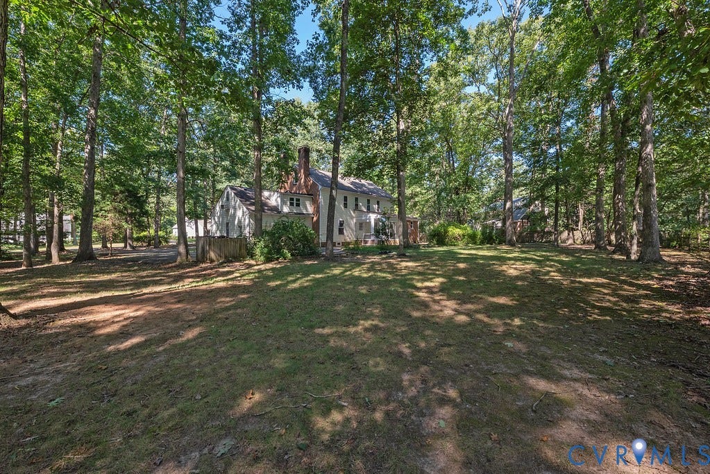13830 Hailsham Circle, Salisbury, Midlothian, VA 23113 Expansive rear yard featuring mature trees, a manicured lawn, and a light-colored siding exterior with a brick chimney