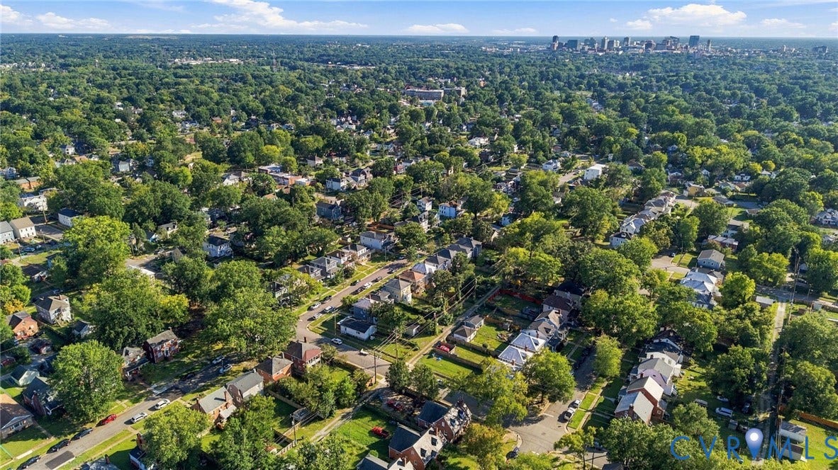 3504 Delaware Avenue, Richmond, VA 23222 Aerial perspective of a verdant neighborhood with residential properties, mature trees, and a distant city skyline