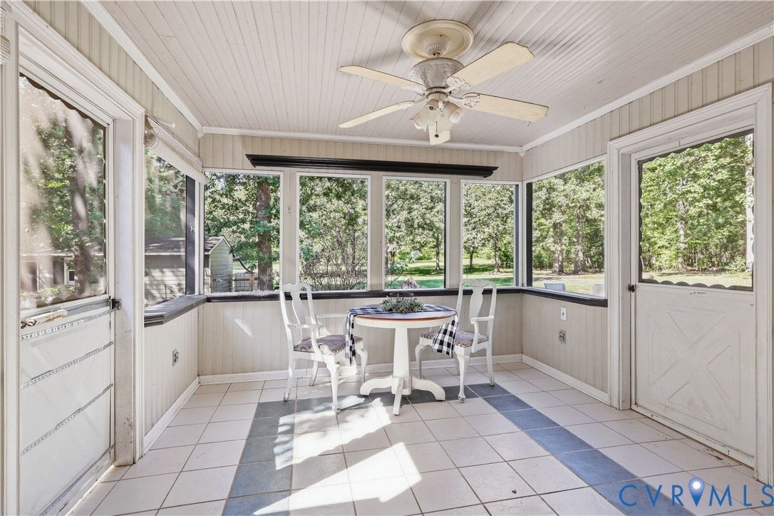 Enclosed porch featuring a ceiling fan, tiled flooring, wood paneling, multiple windows, and two access doors