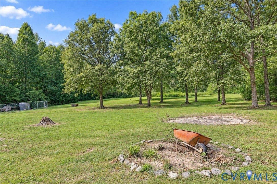 Expansive lawn area with mature trees and a fenced enclosure