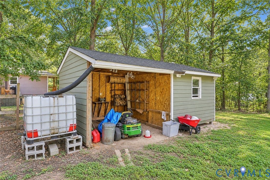 Shed structure featuring horizontal siding, an open-sided storage area with plywood walls, a shingle roof, and a single window