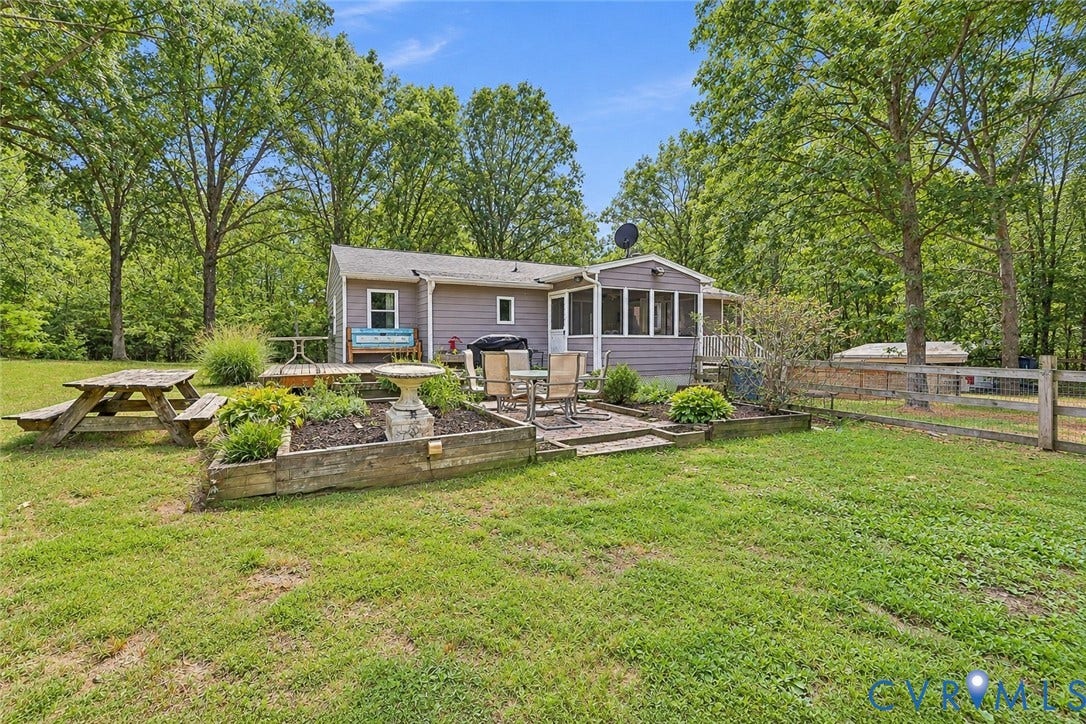 Expansive backyard featuring a screened porch, paver patio, raised garden beds, and a wood fence