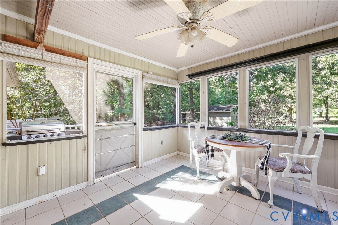 Enclosed porch with paneling, tile flooring, and multiple windows