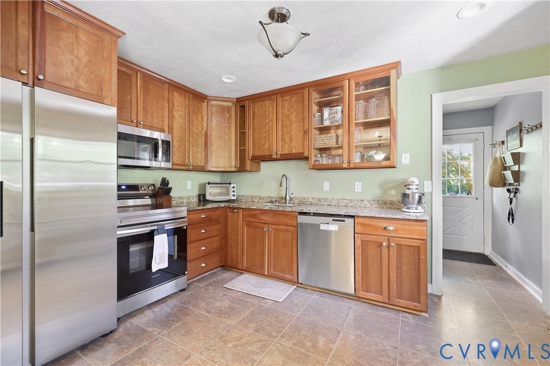 Kitchen featuring wood cabinetry, stainless steel appliances, speckled countertops, and tile flooring