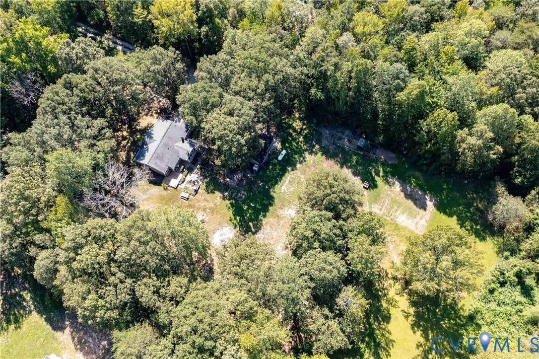 Expansive property surrounded by mature trees, featuring a secluded residence with a dark-toned roof