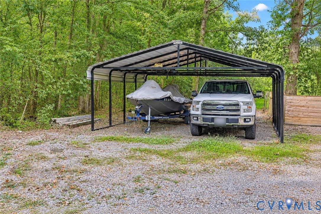 Covered carport with sturdy metal frame and peaked roof design provides sheltered parking for vehicles and additional storage